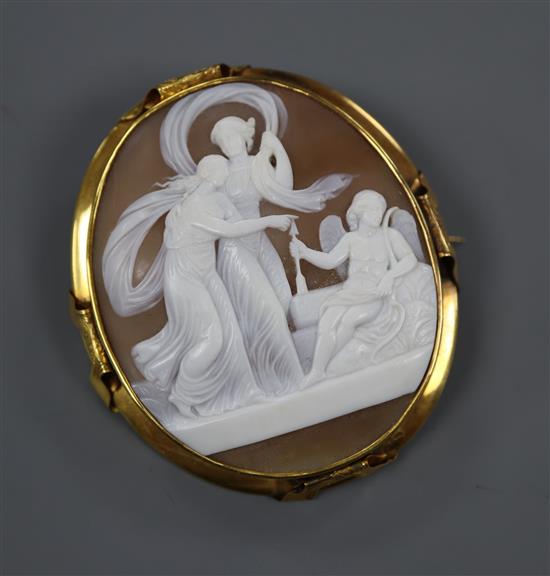 An early 20th century yellow metal mounted oval cameo brooch, carved with Cupid, Venus and Psyche, 68mm.